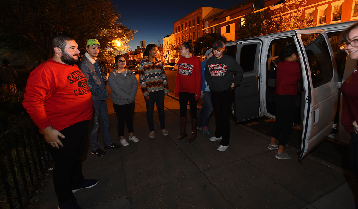 Students standing outside van in the dark